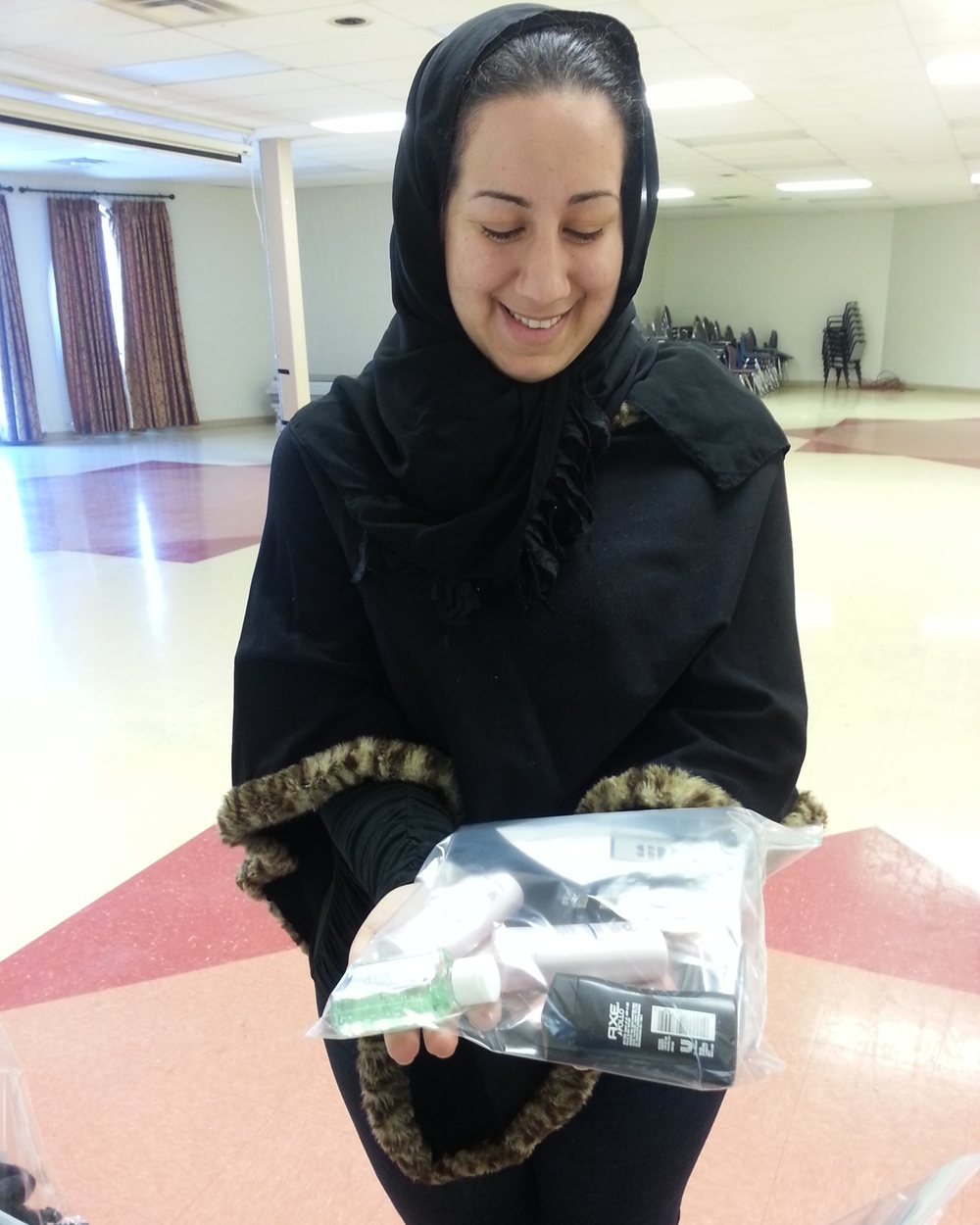 A volunteer smiling as she holds up a packed hygiene kit